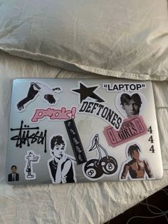 the laptop is covered with stickers and has been placed on top of a bed