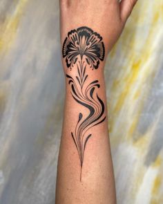 a woman's arm with a black flower tattoo on the left side of her wrist