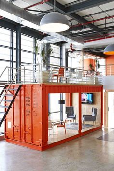 a red container is in the middle of a large room with stairs and windows on it