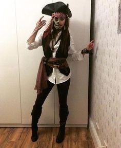 a woman dressed up as a pirate standing in front of a wall with her hands out