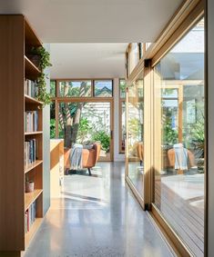 an empty room with bookshelves, couches and plants in the window sill