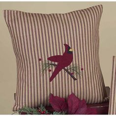 two decorative pillows with cardinals on them sitting next to a christmas tree and potted plant