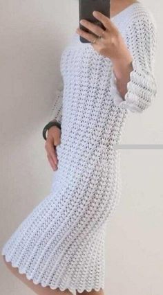 a woman is taking a selfie while wearing a white crochet sweater dress