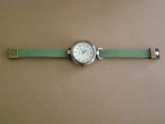 This is a round 1.25 inches diameter watch, made in alloy, aged bronze appearance, quartz with battery, analog. The wrist strap is made with synthetic green suede. The clasp is magnetic also made in alloy , aged bronze appearance. The strap comes in 5 measures: XS (for a 6 inches wrist), S (for a 6.25 inches wrist), M (for a 6.50 inches wrist), L (for a 6.75 inches wrist), XL (for a 7 inches wrist). NOTE: You can measure your wrist (no to tight, no too loose) with a thread, cord, strip of paper, Adjustable Green Analog Watch, Everyday Green Quartz Watch, Classy Watch, Simple Watches, Green Watch, Minimalist Watch, Retro Watches, Unisex Watches, Casual Watches