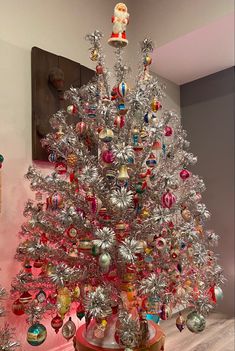 a silver christmas tree sitting on top of a wooden table