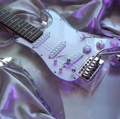 an electric guitar laying on top of a purple sheet