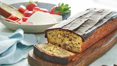 a loaf of cake sitting on top of a cutting board next to a bowl of fruit