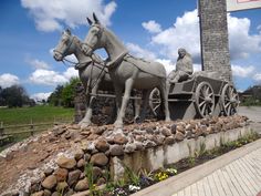 a statue of two horses pulling a carriage with a man on it's back