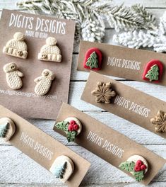 four christmas themed buttons are displayed on brown cards with white snowflakes and pine cones