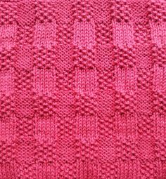 a pink knitted blanket with small squares