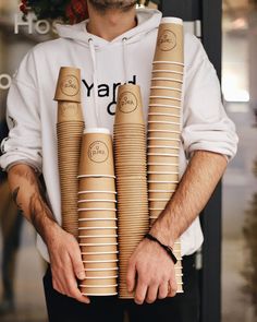 a man holding stacks of coffee cups in his hands