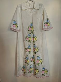 "Vintage 70s handmade Chriffronelle embroidered fabric kaftan. Sheer maxi kaftan with floral embroidery in amazing vintage condition. Beautiful detailing along hem and sleeves with pink embroidered, scalloped border. Floral embroidery in pink, yellow, blue, and green. Dress features 3/4 length bell sleeves, v-neck, collar in front and back with zip and hook and eye closure. Material listed as chiffronelle polyester and pima cotton. Size not listed, as dress is handmade, but would fit up to a siz Spring V-neck Kaftan With Chikankari Embroidery, Spring Multicolor Embroidered Floral Kurta, Spring Floral Print Kurta With Multicolor Embroidery, Spring Folk Style Embroidered Kaftan, Embroidered Folk Style Kaftan For Spring, Spring Folk Kaftan With Multicolor Embroidery, Spring Folk Style Kurta With Embroidered Border, Folk Style Spring Kurta With Embroidered Border, Vintage Embroidered V-neck Dress