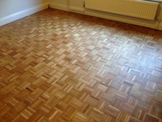 an empty room with hard wood flooring next to a radiator and window