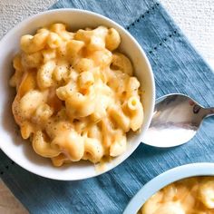 two bowls filled with macaroni and cheese on top of a blue place mat