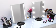 a vanity with lighted mirrors and various makeup products on it, including lipstick, eyeliners