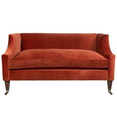 an orange velvet couch with brass legs