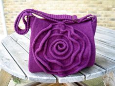 a purple purse sitting on top of a wooden table