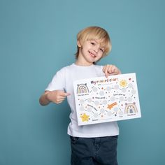 a young boy holding up a birthday card with rainbows and stars on it in front of a blue background