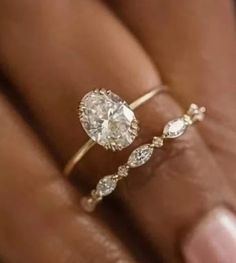 a woman's hand holding a ring with a diamond in the middle and an oval shaped