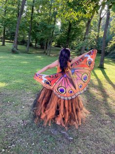 a woman dressed as a butterfly standing in the grass