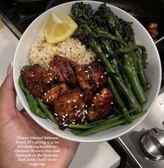 a bowl filled with chicken, broccoli and rice next to a lemon wedge