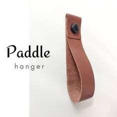 a leather pouch hanging on the wall next to a sign that says paddle hanger