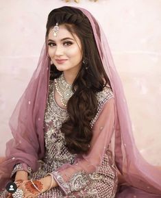 a woman in a bridal outfit sitting on the floor with her hands clasped to her chest