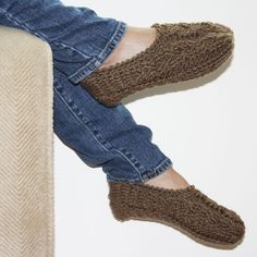 a person wearing slippers sitting on top of a couch next to a white wall