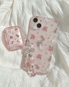 two clear cases sitting on top of a white bed covered in pink and silver flowers