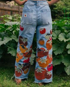 a woman standing in the grass with her hands on her hips and wearing blue jeans