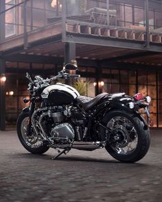 a black and white motorcycle is parked in front of a building with balconies