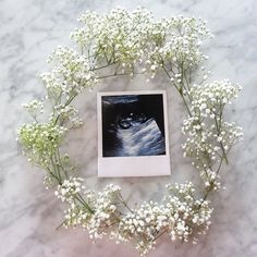 a photo frame with flowers and baby's breath on a marble table top next to it