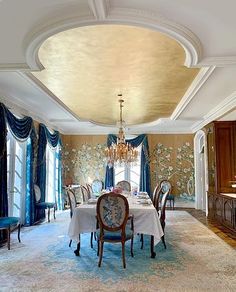 the dining room is decorated with blue and gold wallpaper, chandelier, and chairs