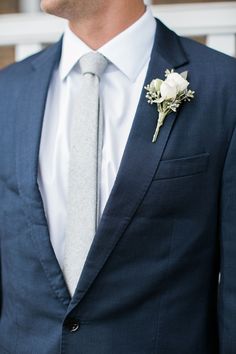 a man in a suit and tie with a boutonniere on his lapel