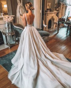 a woman in a wedding dress looking at herself in the mirror with her back to the camera