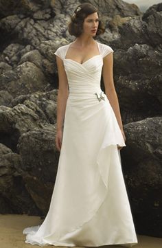 a woman in a white wedding dress standing on rocks