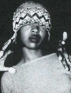 a black and white photo of a woman wearing a knitted hat with her hands in the air