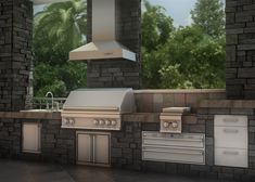 an outdoor kitchen with grills, sink and cabinets on the outside wall in front of trees