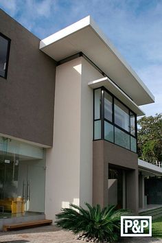 a modern house with large windows and plants in the front yard