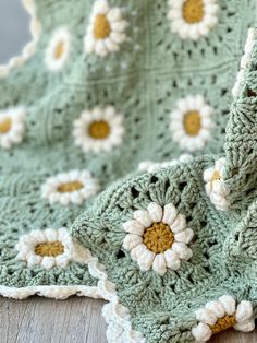 a crocheted blanket with white and yellow flowers