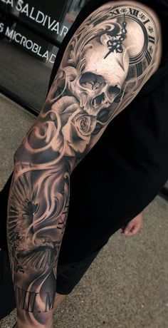 a man with a skull and roses tattoo on his arm