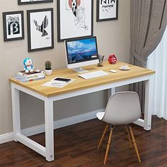 a desk with a computer on top of it in front of some pictures and paintings