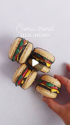 a hand is holding three mini sandwiches made out of paper and painted with food colorings