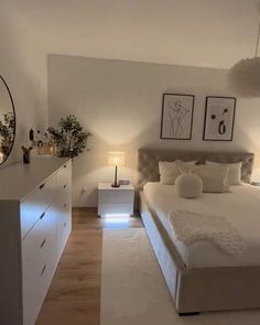 a large white bed sitting in a bedroom next to a dresser and lamps on either side of the bed