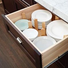 an open drawer in a kitchen filled with dishes