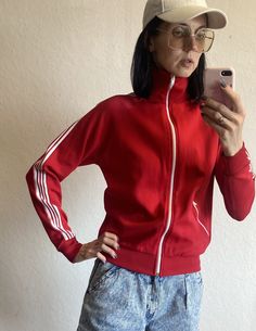 Lovely unisex athletic sports jacket from 1970s by Sports Master. The sweatshirt tight fit. Main colour is beautiful deep red and it has white stripes on sleeves and shoulders. Full zip closing. One pocket with zipper closing. High roll up collar. The fabric is 45 cotton and 55% nylon. Estimated current size : EU 34-38 US 2-6 UK 6-10 The model on the photos is 174 cm tall; bust 86 cm, waist 66 cm, hips 89 cm (EU 34-36). NB! FOR EXPRESS DELIVERY WITH DHL I NEED YOUR E-MAIL ADDRESS AND PHONE NUMBE Red Track Jacket With Ribbed Cuffs For Sports, Vintage Red Long Sleeve Track Jacket, Vintage Long Sleeve Track Jacket With Ribbed Cuffs, Sporty Red Cotton Track Jacket, Sporty Fitted Track Jacket For College, Fitted Long Sleeve Vintage Sweatshirt, Fitted Vintage Long Sleeve Sweatshirt, Fitted Sporty Track Jacket For College, Red Athleisure Track Jacket For Fall