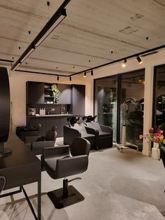 a living room filled with black furniture and lots of glass doors leading to an outside patio