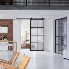 an open living room with wooden chairs and brick walls