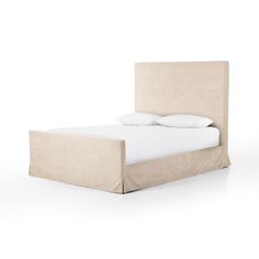 an upholstered bed with two pillows on it