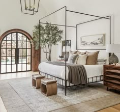 a bedroom with a canopy bed and wooden dressers in front of an arched window